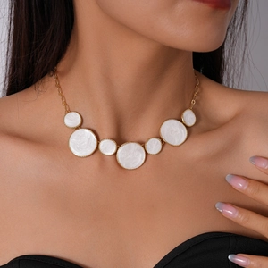 Détail d'un collier doré avec plusieurs pendentifs ronds blancs en émail pour femmes