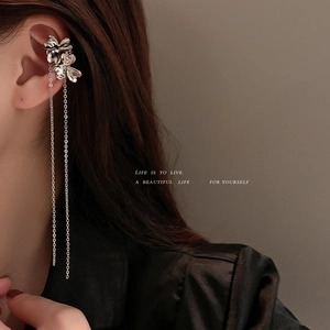 Detail view of silver floral ear cuff with long tassel chains worn by a model