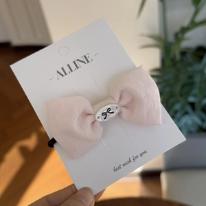 Detail of a pink cotton linen bow hair tie with an oval motif on a display card