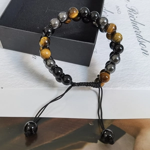 Detalle de pulsera ajustable de ojo de tigre y obsidiana con cordón tejido negro