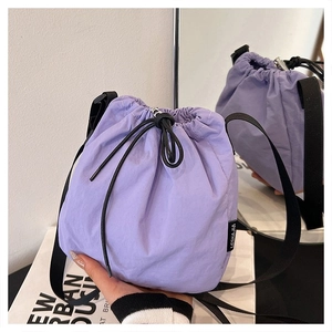 Detail of purple nylon drawstring bucket bag with black strap reflected in a mirror