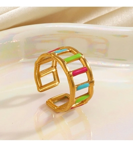 Dettaglio macro di anello regolabile dorato con smalto rosa blu verde e intagli trapezoidali