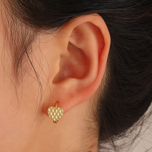 Golden heart earrings with diamond texture shown on ear for a stylish fashion look