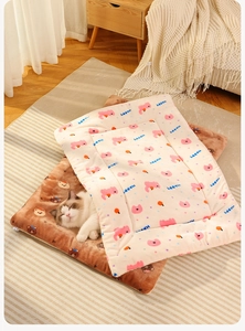 Detalle de manta suave para mascotas con estampados de dibujos y un gato durmiendo feliz