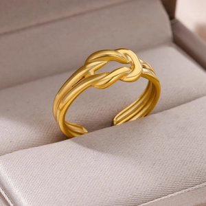 Macro shot of gold-plated knot ring with three-line band on champagne silk texture