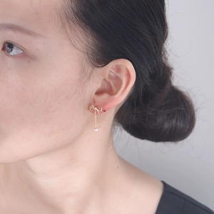 Nahaufnahme von goldenen Schleifenohrringen mit zarter weißer Perle am Modellohr