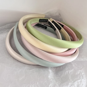 Detail of stacked handmade satin headbands in soft pastel colors like pink and green
