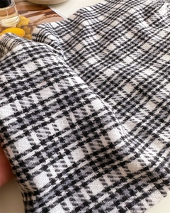 Close-up of black and white plaid cashmere-like fabric showing thick woven texture and tassels