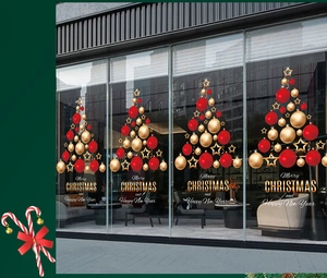 Détail d'un autocollant de Noël composé de boules rouges et dorées sur une porte vitrée
