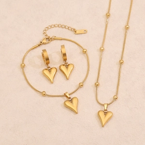 Flat lay of gold heart jewelry set including necklace, bracelet and earrings on white background