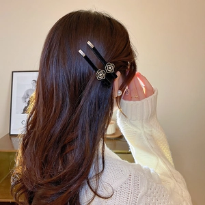 Detail view of black velvet camellia hair clips with gold trim and pearl centers