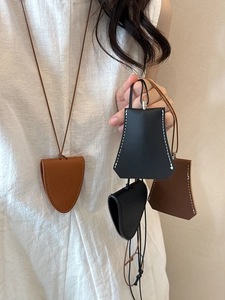 Detail of leather clochette bag pendant showing contrast stitching and hanging cord
