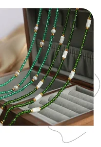 Gros plan d'un collier de perles en cristal vert sur un coffret à bijoux en bois chic