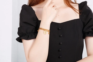 Detail view of a double-layer gold chain bracelet with rectangle poker card pendant