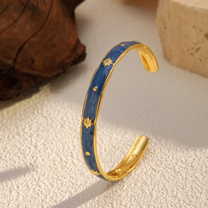 Detail of 18K gold plated C-shape cuff with blue marble enamel and star studs