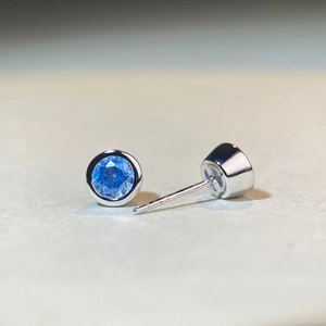 Macro shot of silver stud earrings featuring 0.5ct round blue zircons and bubble setting