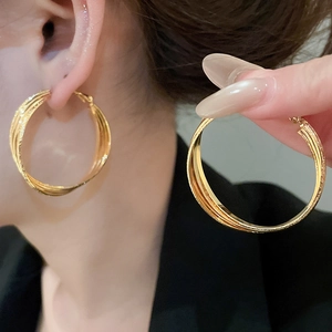 Détail de créoles entrelacées multicouches plaquées or 18 carats sur modèle et en main
