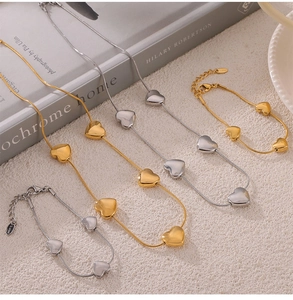 Detail view of heart charm necklaces and bracelets on textured beige fabric with book