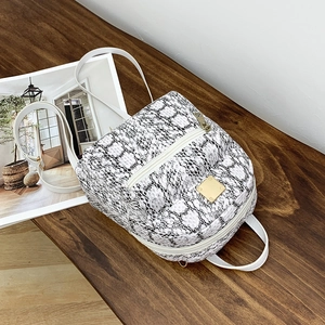 Close-up of white snakeskin pattern backpack with golden metal logo and front zipper