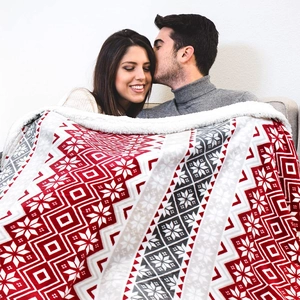 Cozy couple wrapped in a red snowflake Christmas Sherpa blanket on a minimalist sofa