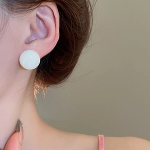 Close-up of elegant white round stud earring on model showing perfect size and fit