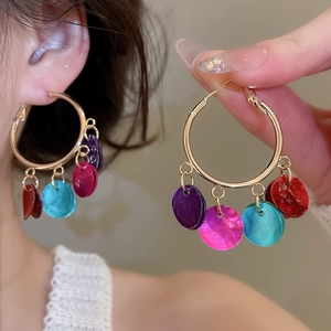 Detail of bohemian gold hoop earrings with colorful shimmering sequin disc charms on model
