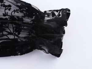 Dettaglio del polsino in pizzo nero trasparente con texture floreali e volant