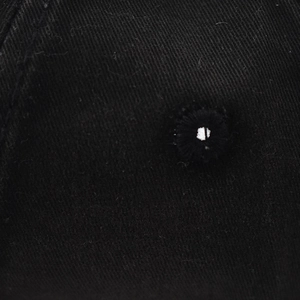 Close-up of high-quality embroidery eyelet and twill fabric texture on a black cotton cap