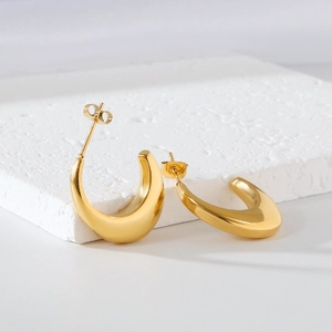 Macro shot of gold-plated irregular thick hoop earrings on a natural white stone base