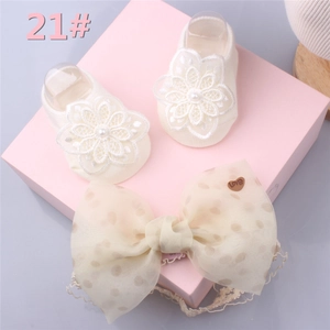 Detail view of baby socks and headband set with lace flowers, pearls and bow on pink box