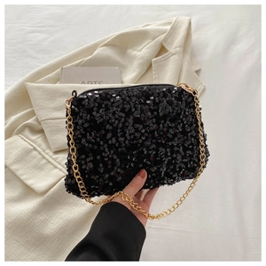 Detail of a sparkling black sequin crossbody bag with a gold metal chain strap