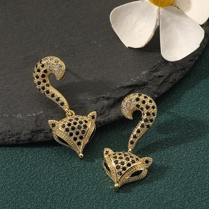 Macro detail of gold leopard ear studs with black and clear crystals on dark stone