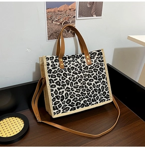 Close-up of black and white leopard print tote with beige linen trim and golden rivets