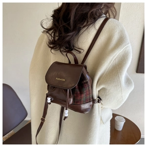 Detailansicht eines Vintage-Mini-Rucksacks in Braun mit rot-grünem Karomuster und Logo
