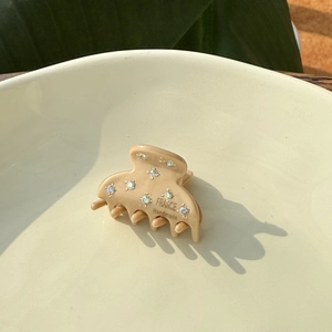 French style mini acetate hair claw clip with rhinestones in khaki on ceramic plate