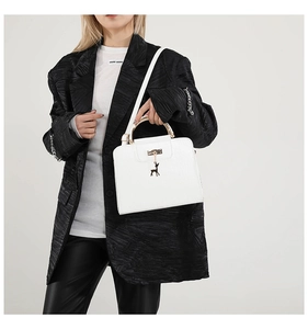 Detail of white crocodile pattern handbag with golden handle and deer charm