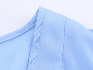 Detailed close-up of the light blue neckline featuring precise stitching and linen texture