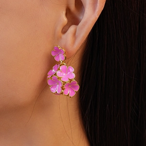 Boucles d'oreilles fleurs 3D rose et doré portées par un mannequin femme élégant