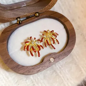Boucles d'oreilles feux d'artifice rouges avec placage or et cristaux étincelants sur socle