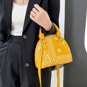 Detail of yellow shell bag with white paisley pattern and golden metal hardware