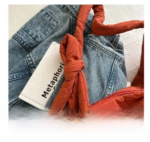 Detail shot of caramel quilted tote bag with bow knot and metal zipper on denim