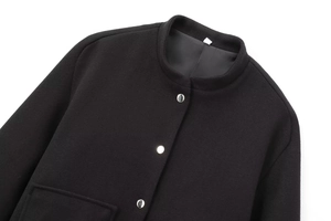 Detail view of premium black wool bomber jacket featuring metallic silver button closure