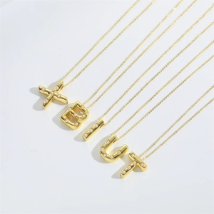 Detailed close-up of golden letter pendants with white pearl inlay on a white surface