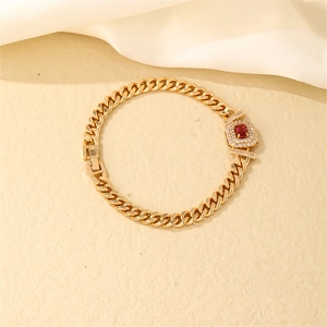 Detailed close-up of golden Cuban link bracelet with rectangle red stone and zircon