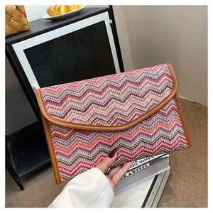 Detail of colorful zigzag woven straw envelope bag with brown faux leather trim