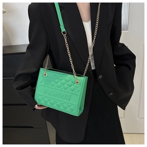 Close-up of green embossed handbag with gold chain strap and FASHION lettering detail