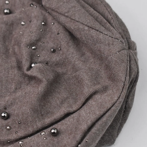 Close-up of dark brown knit fabric with decorative black metal beads and fine texture