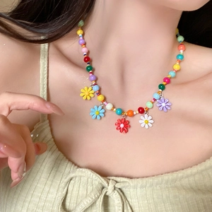 Close-up of colorful beaded choker with daisy pendants on a model neck