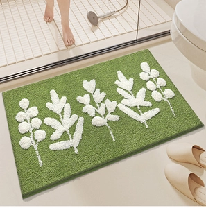 Close-up of green rectangular bath mat with white leaf pattern on bathroom tile
