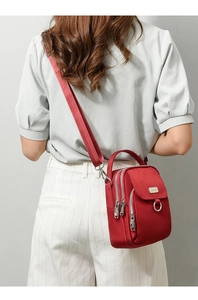 Rear view of a model wearing a red multi-compartment nylon crossbody bag with wide strap